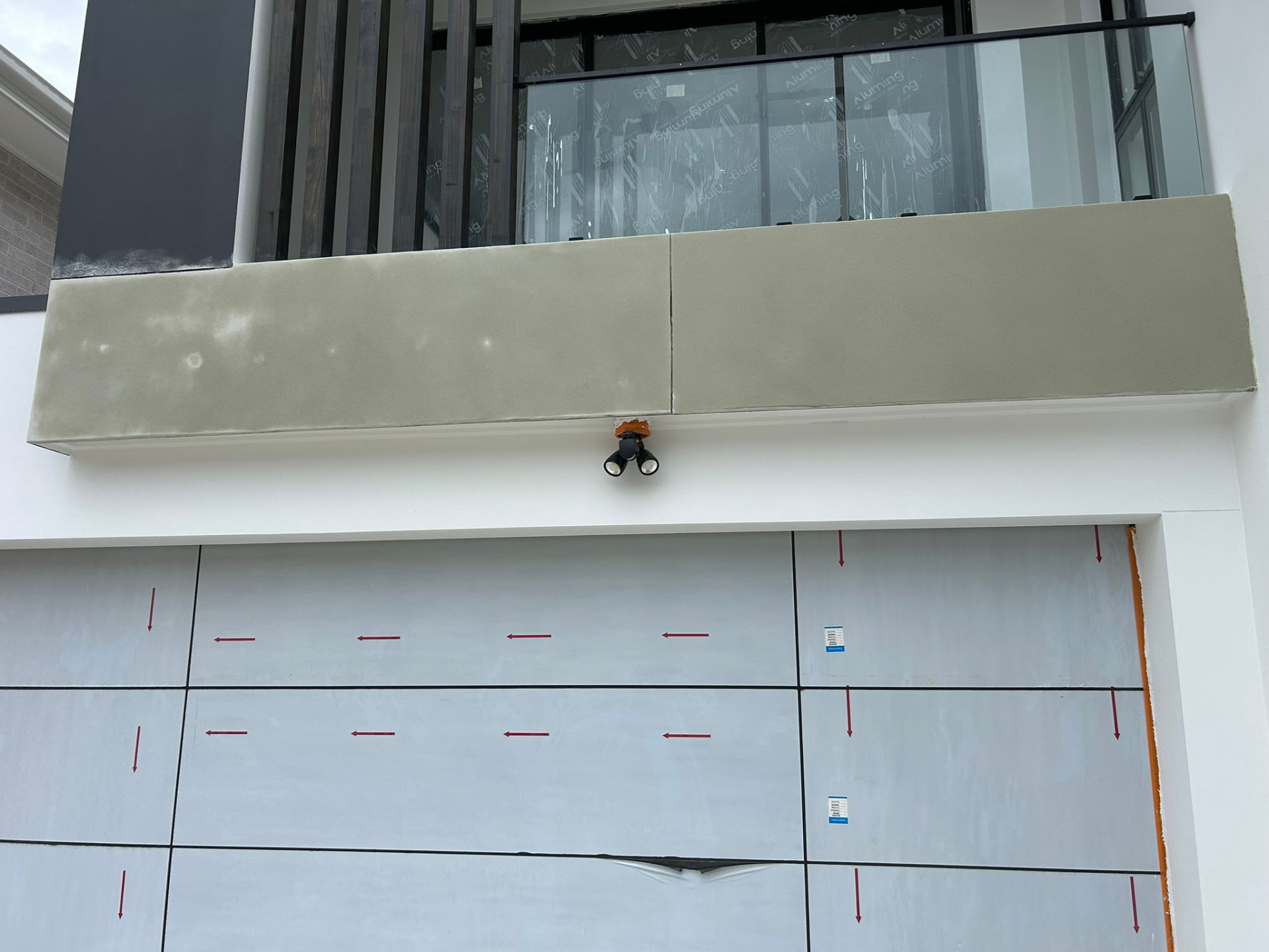 Rendered balcony face above a protected garage door on a building under construction
